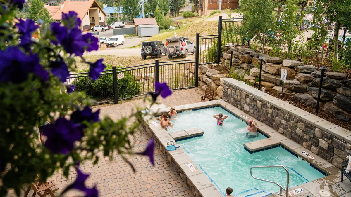 This exterior image showcases a jacuzzi and swimming pool surrounded by lush greenery and vibrant flowers, creating an inviting and tranquil atmosphere. The scene hints at opportunities for relaxation, socializing, and enjoying poolside leisure.